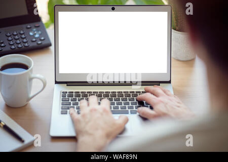 Man with laptop computer on desk working in office with blank screen Stock Photo
