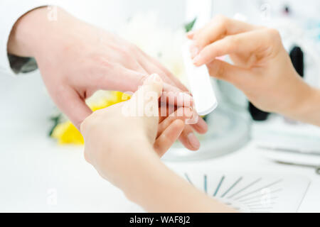 Woman filing fingernails of a man in nail parlor Stock Photo