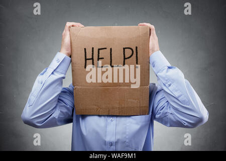 Cardboard box on businessman head asks for help concept for problems, support, overworked or stress Stock Photo