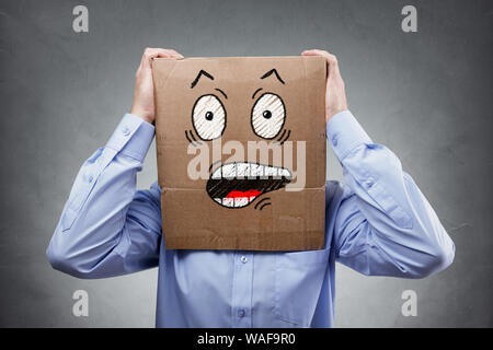 Businessman with cardboard box on his head showing a shocked and surprised expression expression concept for failure, surprise, fear, anxiety or disbe Stock Photo