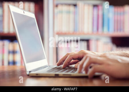 Hands typing on laptop computer in library concept for education, writer or research Stock Photo