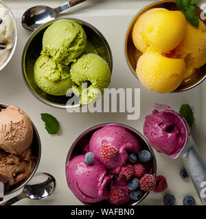 Assorted flavors and colors of gourmet Italian ice cream served on steel table. Mango, chocolate, green matcha ice cream Stock Photo