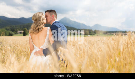 Bride and groom kissing and hugging tenderly in wheat field somewhere in Slovenian countryside. Stock Photo