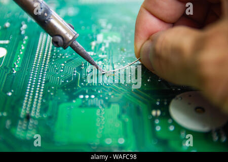 Technicians are using a soldering iron for repairing electronic of the computer circuit board concept technology of computer circuit hardware. Stock Photo