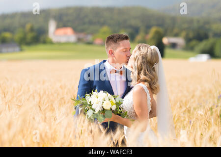 Bride and groom kissing and hugging tenderly in wheat field somewhere in Slovenian countryside. Stock Photo