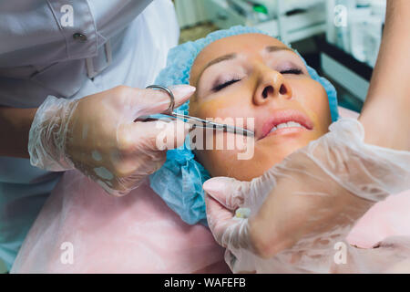 Close up of a hands threading beautiful womans upper lip. Stock Photo