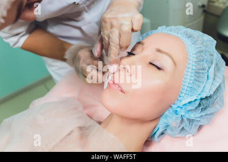 Close up of a hands threading beautiful womans upper lip. Stock Photo