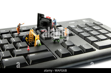 little world figures repairing the key board of the computer or try to hack or intergate in the system Stock Photo