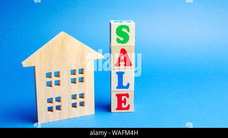 Wooden blocks with the word Sale and wooden miniature house. The concept of the sell of real estate, apartments and residential premises. Rent and mor Stock Photo