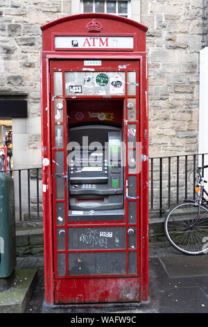 Britain's iconic but grubby red phone box converted into cash machine ATM in the High Street Royal Mile in Edinburgh Scotland UK. Stock Photo