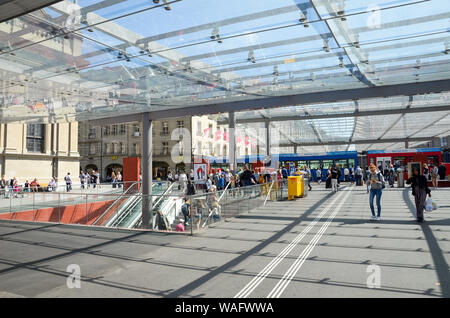 Bern, Switzerland - August 14 2019: People walking under the roof by tram station. The station is adjacent to the main train station. Tram in background. Public transport. Daily life. Swiss capital. Stock Photo