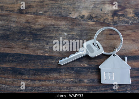 Key and House Pendant on a Rustic Wooden Background. Stock Photo