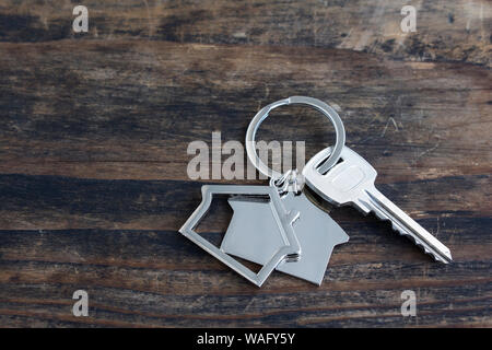 Key and House Pendant on a Rustic Wooden Background. Stock Photo