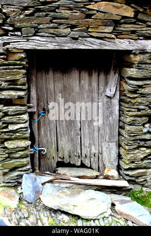 Rustic hand-hewn wood door set into a stone wall built from schist in Piodão, made of shale rocks stack, one of Portugal's schist villages in the Alde Stock Photo