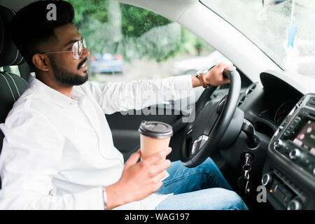 transportation and vehicle concept - man drinking coffee while driving the car Stock Photo