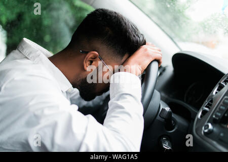 Drunk man slumped on steering wheel in his car Stock Photo