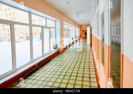 Perspective view of an old school or office building corridor , empty narrow, high and long , with many room doors and Windows. The interior design an Stock Photo