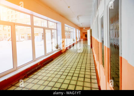 Perspective view of an old school or office building corridor , empty narrow, high and long , with many room doors and Windows. The interior design an Stock Photo