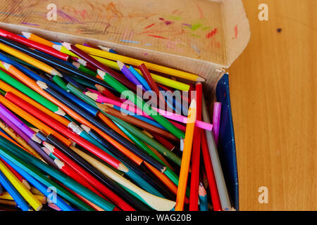 A lot of Old and broken colorful Pencils in cardboard box. Stock Photo