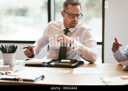 Mature businessman going over documents while sitting at a table in an office boardroom during a meeting Stock Photo