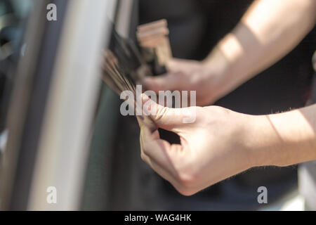 Tinted dark glass foil removal from car window. Stock Photo by