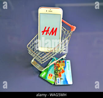 Yaroslavl, Russia - AUgust 20, 2019: Smartphone with H&M logo in shopping cart and credit cards on the table. Stock Photo