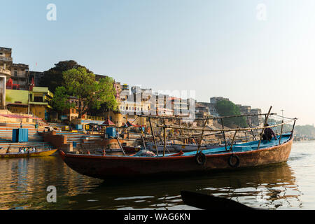 Ethnic boatman rowing wooden boat at sunrise in Ganges River near Ghat Stock Photo