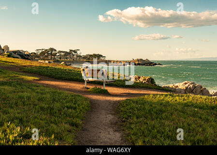 An empty bench in front of the ocean at sunset Stock Photo