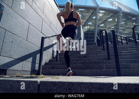 Blondie woman trained legs during jogging on a strairs Stock Photo