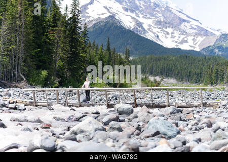 Hiker is standing on the log bridge at Mt Rainier National Park Stock Photo