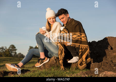 Man and woman dressed in coats on a sunny afternoon, having something hot. Stock Photo