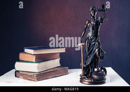 Themis figurine stands on a white wooden table next to a stack of old books. Scales Law Lawyer Business Concept. - Image Stock Photo