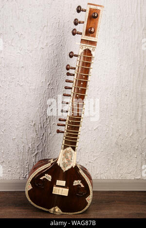 Indian musical instrument sitar standing next to the grey wall - image Stock Photo