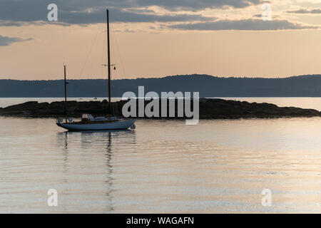 A concordia yawl Sits on a mooring off Pumpkin Island, Maine at sunset Stock Photo