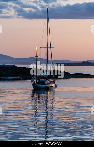 A concordia yawl Sits on a mooring off Pumpkin Island, Maine at sunset Stock Photo