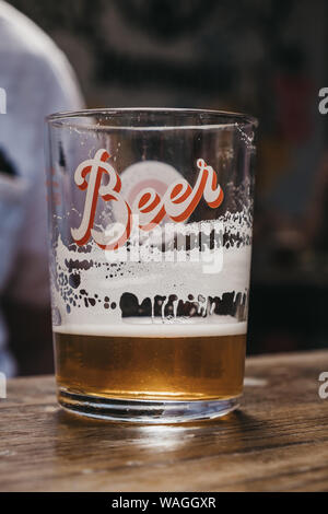 Close up of a nearly empty beer glass with a modern 'Beer' writing, on a wooden table, selective focus. Stock Photo