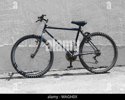 black old bicycle, mountain bike next to a white wall