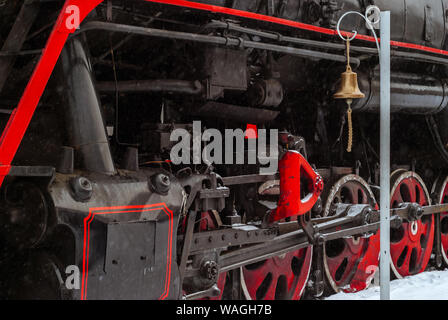 closeup of a steam locomotive wheels with valve gear and station bell Stock Photo