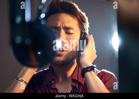 young asian adult man enjoying singing a song in modern recording studio Stock Photo