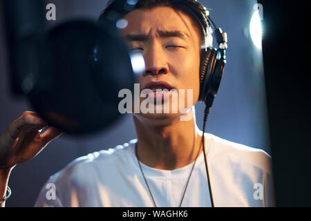 young asian adult man enjoying singing a song in modern recording studio Stock Photo