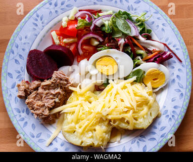 Plate of mixed green salad consisting of tuna, boiled egg, baked potato, cheese, beetroot, pickled onions, tomatoes and lettuce Stock Photo