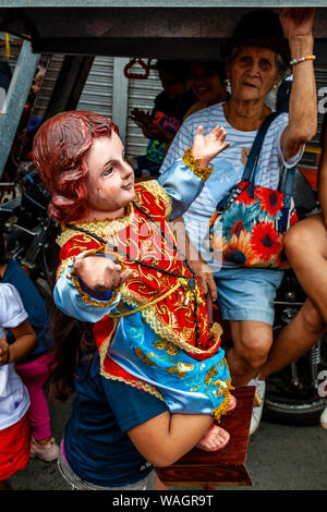 A Child Carrys A Santo Nino Statue Through The Streets Of Kalibo During The Ati-Atihan Festival, Kalibo, Panay Island, The Philippines. Stock Photo