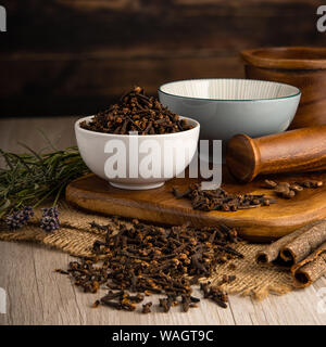 Whole Cloves in a bowl and food preparation and kitchen setting Stock Photo