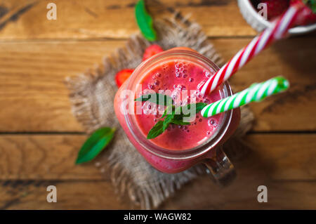 Strawberry smoothie in a glass jar with fresh mint, on wooden background, top view Stock Photo