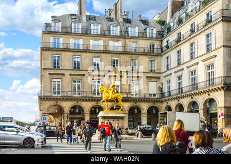 A gilded bronze equestrian sculpture of Joan of Arc by Emmanuel Frémiet in the Place des Pyramides in Paris France as tourists walk the intersection Stock Photo