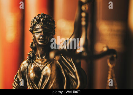 Brass figure of Justice wearing a blindfold holding up scales symbolic of the law in a close up dark moody image Stock Photo