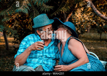 Senior couple kissing while drinking wine together on a picnic in the park Stock Photo