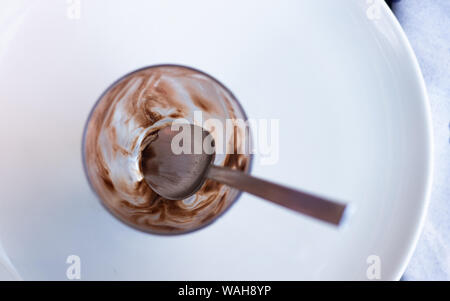 On a white round plate, close up of the bottom of a desert cup which was filled with chocolate ice cream. Calories counting concept, diet, frustration Stock Photo