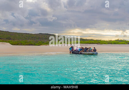 Tourists having a wet landing from a zodiac tour boat on the beach of Bahia Gardner or Gardner Bay, Espanola Island, Galapagos Islands, Ecuador. Stock Photo