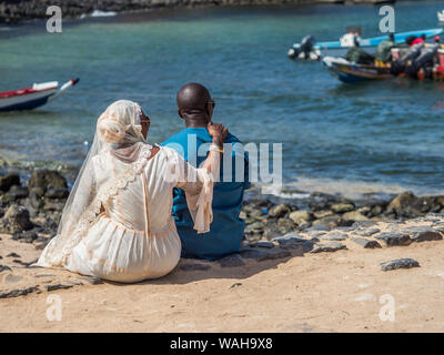 A view of a Senegalese couple in wedding dress sitting by the ocean on the island of Goree. Stock Photo